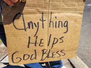 A cardboard sign that reads "Anything Helps, God Bless"